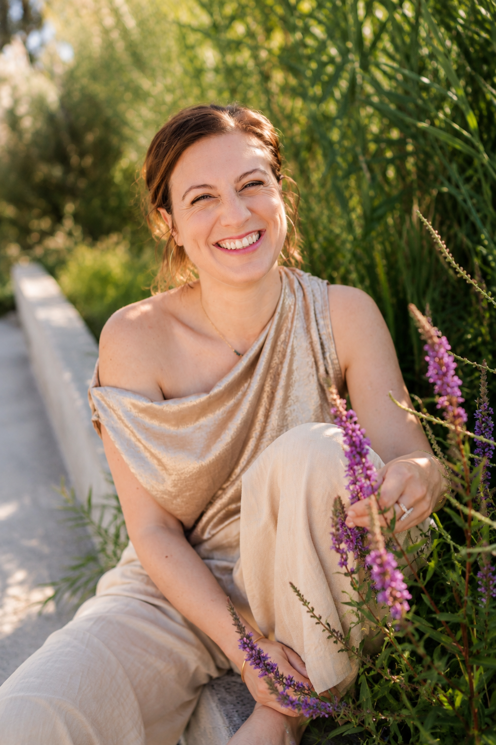 Gaëlle assise parmi les fleurs, en train de rire